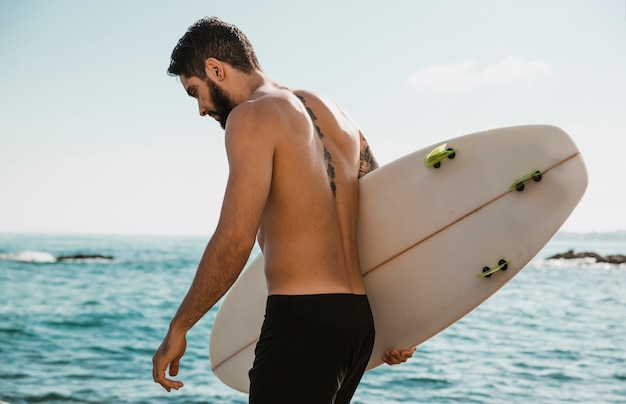 Jeune mâle avec planche de surf près de l&#39;océan
