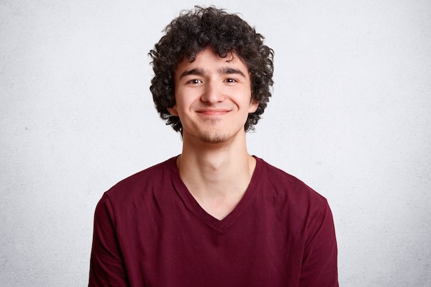 Jeune mâle positif avec des cheveux bouclés