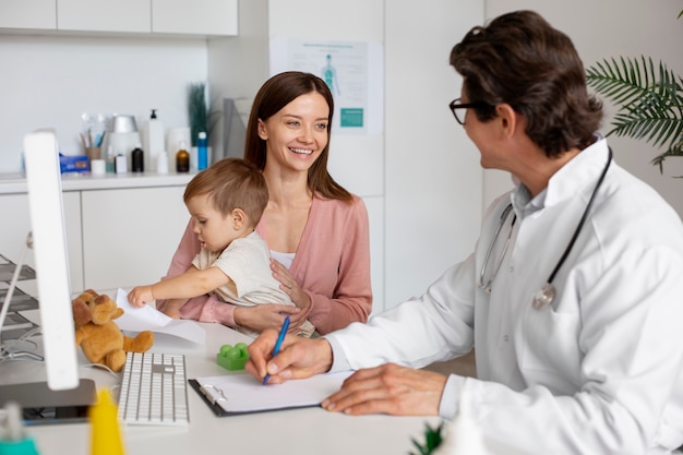 Jeune maman avec bambin chez le pédiatre pour une consultation