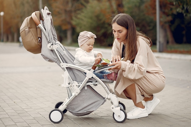 Photo gratuite jeune maman marchant dans un parc en automne avec calèche