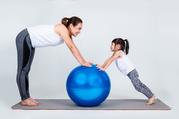 Jeune maman avec petite fille exercer sur ballon de fitness