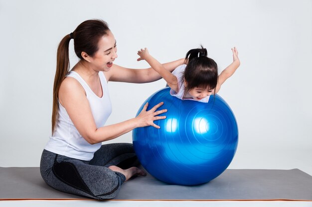 Jeune maman avec petite fille exercer sur ballon de fitness