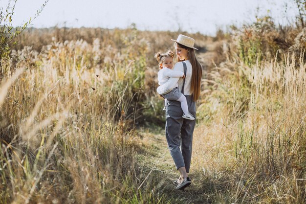 Jeune maman avec sa petite fille dans un champ d'automne