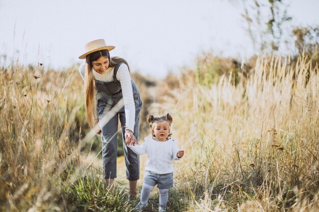 Jeune maman avec sa petite fille dans un champ d'automne