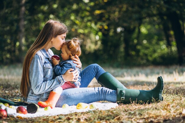 Jeune maman avec sa petite fille dans un parc en automne ayant pique-nique
