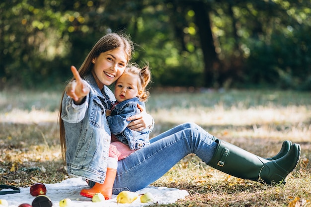 Jeune maman avec sa petite fille dans un parc en automne ayant pique-nique