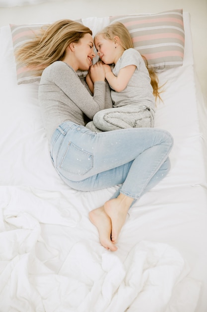 Jeune maman et sa petite fille à la maison au matin ensoleillé. Couleurs pastel douces. Bon temps en famille le week-end. Concept de la fête des mères. Concepts de famille, d'amour, de style de vie, de maternité et de moments tendres.