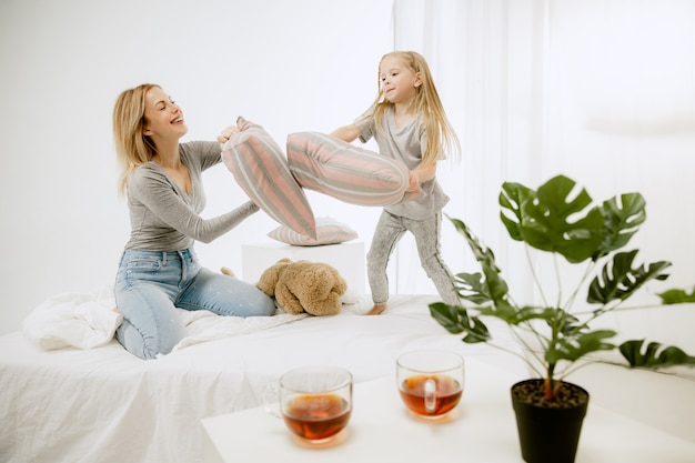 Jeune maman et sa petite fille à la maison au matin ensoleillé. Couleurs pastel douces. Bon temps en famille le week-end. Concept de la fête des mères. Concepts de famille, d'amour, de style de vie, de maternité et de moments tendres.