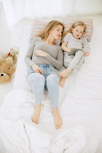 Jeune maman et sa petite fille à la maison au matin ensoleillé. Couleurs pastel douces. Bon temps en famille le week-end. Concept de la fête des mères. Concepts de famille, d'amour, de style de vie, de maternité et de moments tendres.