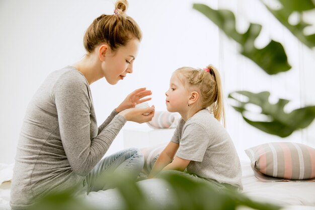 Jeune maman et sa petite fille à la maison au matin ensoleillé.