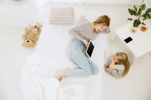 Jeune maman et sa petite fille à la maison au matin ensoleillé.