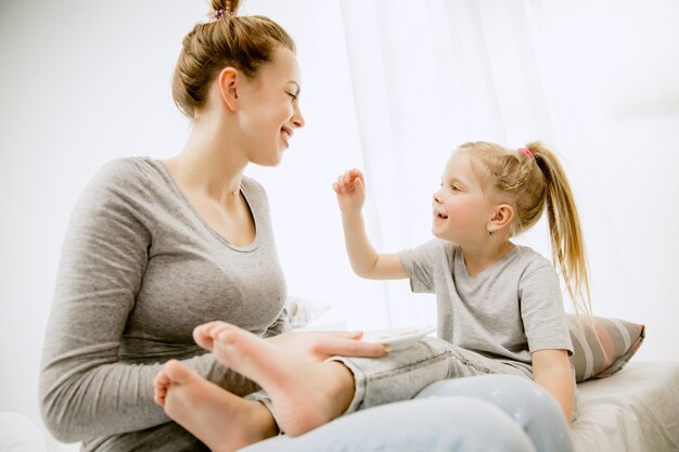 Jeune maman et sa petite fille à la maison au matin ensoleillé.