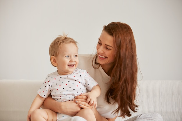 Jeune maman avec son petit-fils d'un an habillé en pyjama se détend
