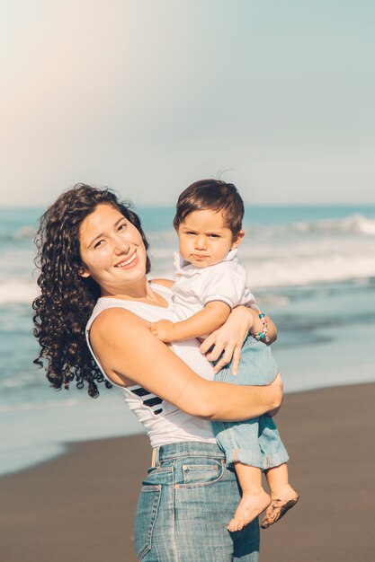 Jeune maman tenant son bébé dans les mains sur la plage