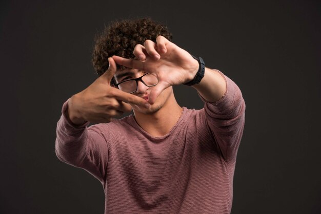 Jeune mannequin aux cheveux bouclés montrant le signe du cadre.