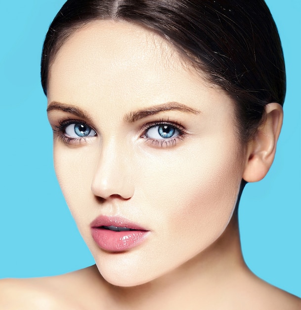 Jeune mannequin caucasien avec du maquillage nue touchant sa peau parfaitement propre sur bleu