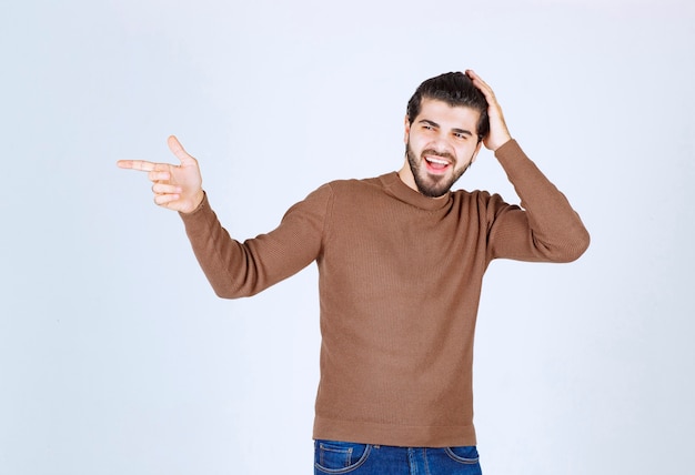 Un jeune mannequin séduisant en pull marron debout sur un mur blanc. photo de haute qualité