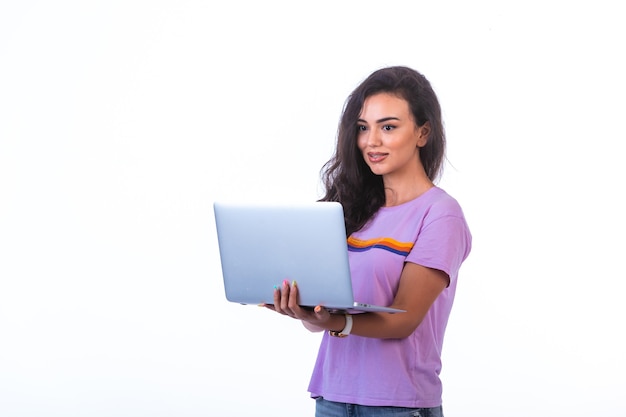 Jeune mannequin tenant un ordinateur portable argenté et ayant un appel vidéo sur fond blanc