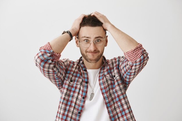 Jeune mec confus et tendu avec des lunettes posant