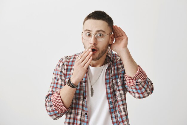 Jeune mec impressionné et excité avec des lunettes posant