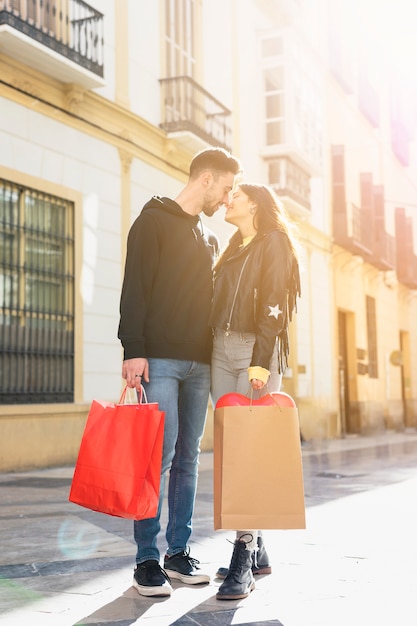 Photo gratuite jeune mec avec des paquets embrassant dame sur la rue