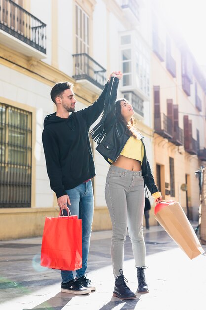 Jeune mec avec des paquets tenant la main de la dame sur la rue