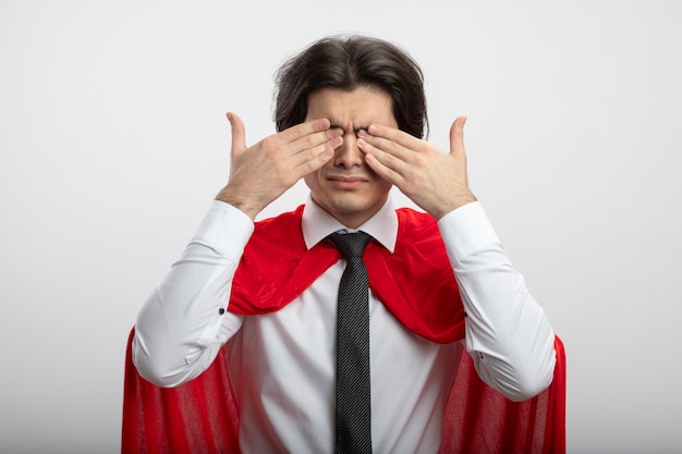 Jeune mec de super-héros portant des yeux couverts de cravate avec les mains isolés sur blanc