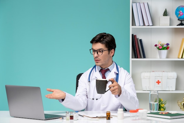 Jeune médecin intelligent en blouse de laboratoire travaillant à distance sur ordinateur parlant au patient