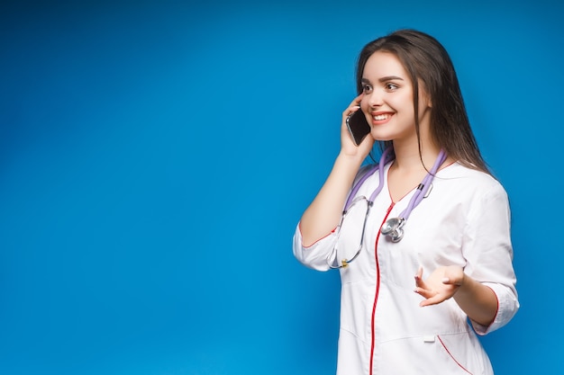 Jeune médecin magnifique parlant par téléphone avec un patient en bleu.
