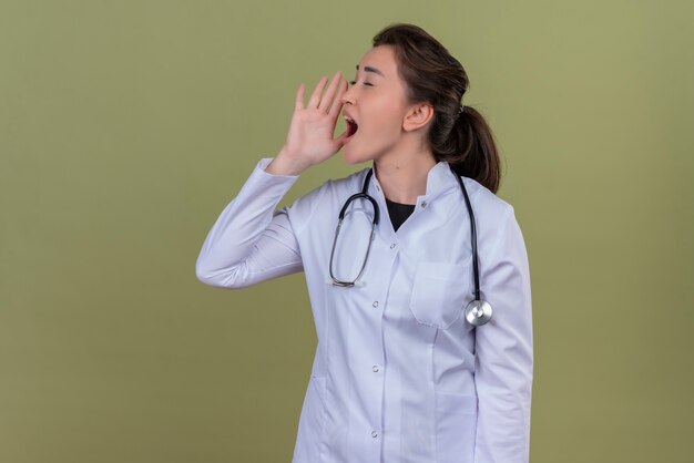 Jeune médecin portant une blouse médicale portant un stéthoscope - sur mur vert