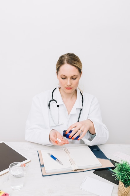 Jeune médecin prenant des pilules au bureau