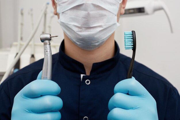 Jeune médecin tenant un outil dentaire et une brosse à dents