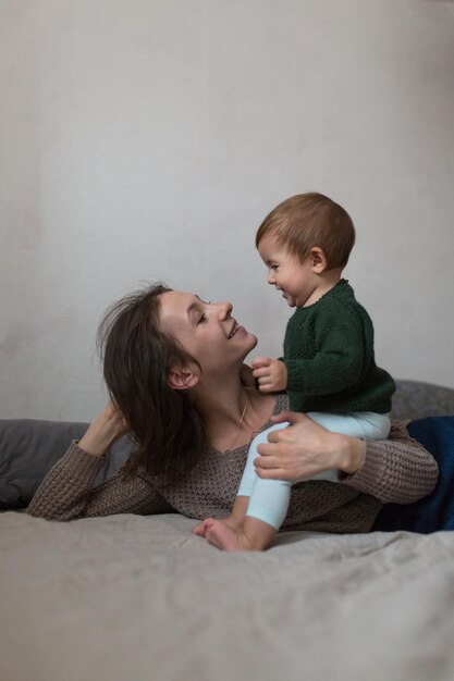 Jeune mère et bébé en chandails tricotés jouant sur le concept de lit style de vie confortable à la maison