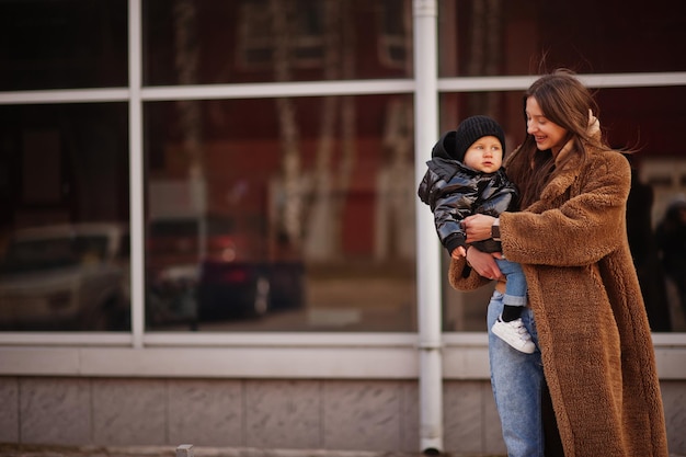 Jeune mère avec enfant sur les mains marchant dans les rues