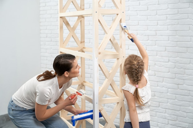 Photo gratuite jeune mère et enfant peinture rack en bois