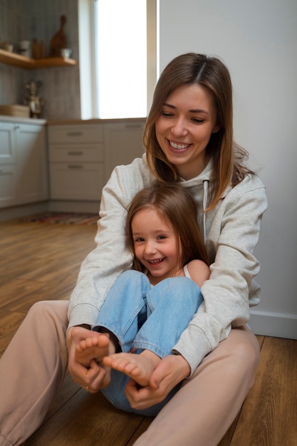 Jeune mère faisant rire sa fille en la chatouillant