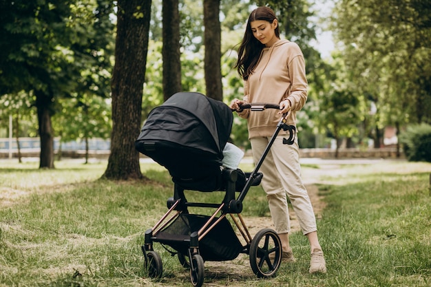 Jeune mère marchant avec landau dans le parc