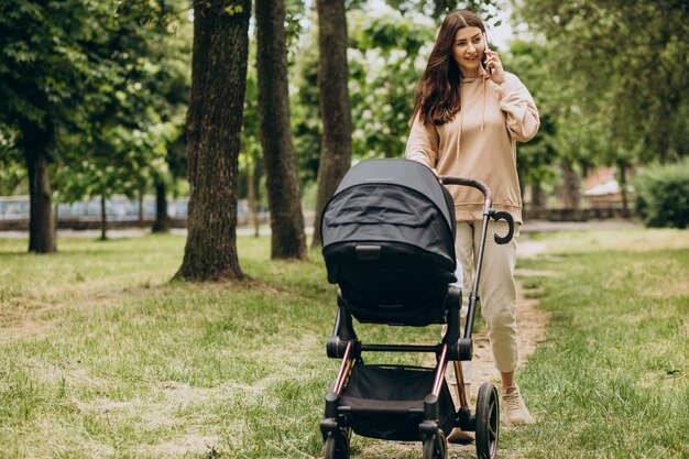 Jeune mère marchant avec landau dans le parc