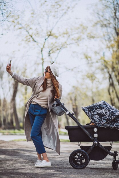 Jeune, mère, marche, voiture bébé, dans parc