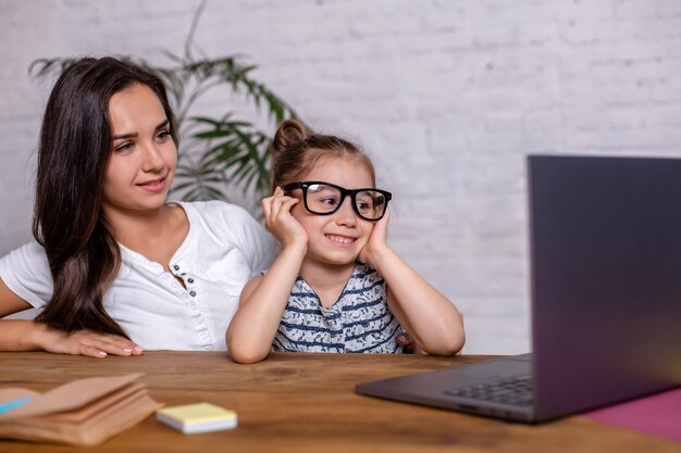 Une jeune mère avec une petite fille fait ses courses sur Internet sur un ordinateur personnel. Concept de magasinage familial en ligne