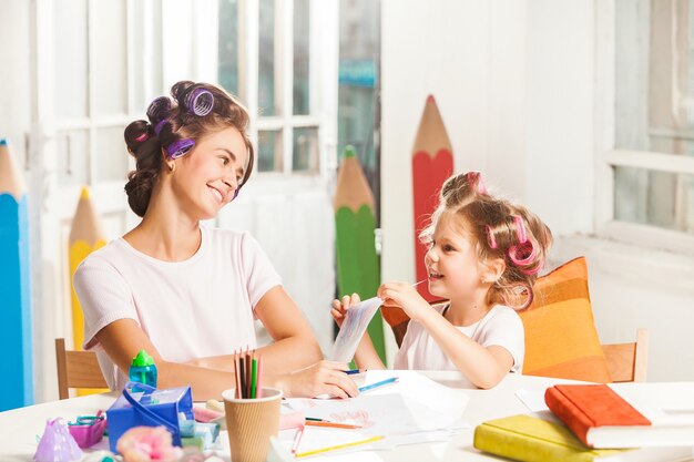 La jeune mère et sa petite fille dessinant avec des crayons à la maison