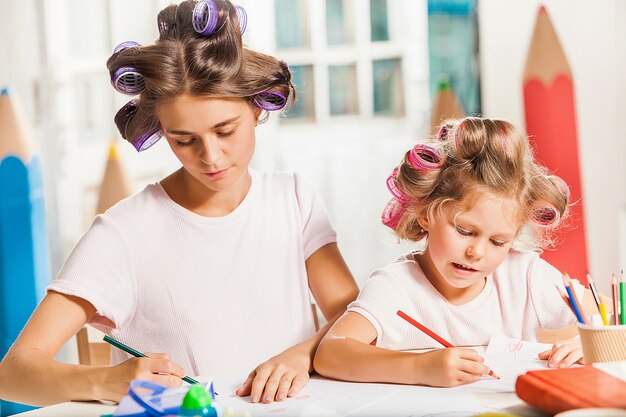 La jeune mère et sa petite fille dessinant avec des crayons à la maison