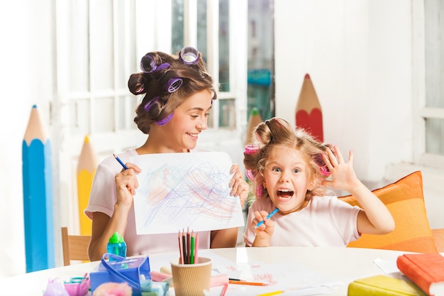 Photo gratuite la jeune mère et sa petite fille dessinant avec des crayons à la maison