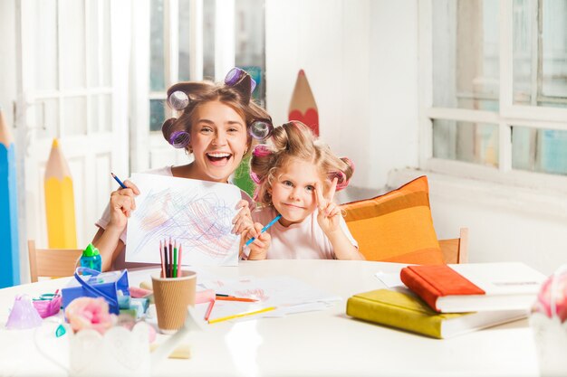 La jeune mère et sa petite fille dessinant avec des crayons à la maison