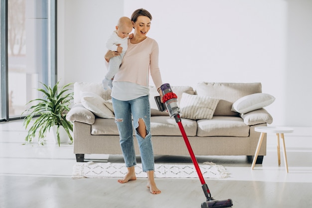 Jeune mère avec son petit garçon nettoyant à la maison