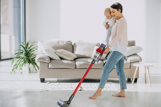 Jeune mère avec son petit garçon nettoyant à la maison