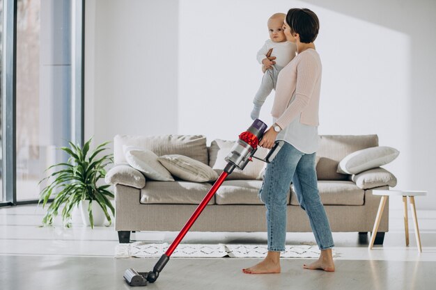 Jeune mère avec son petit garçon nettoyant à la maison