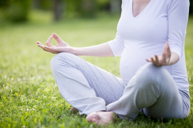 Jeune modèle enceinte méditant à l&#39;extérieur. Fermer