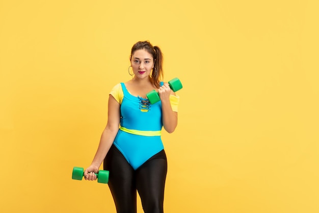 Jeune modèle féminin s'entraînant sur le mur jaune