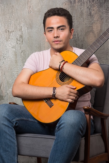 Jeune Musicien Serrant La Guitare Sur Fond De Marbre